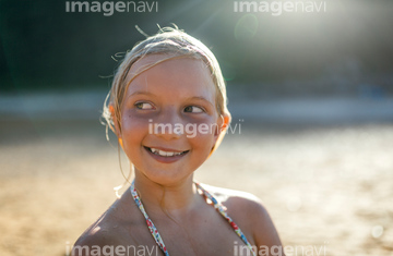 Portrait of girl wearing bikini top leaning against tree