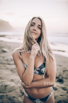 Young blond woman wearing bikini at the beach and looking at