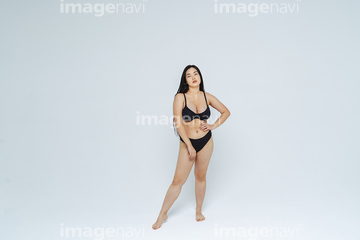 Skinny female model wearing bikini standing against white