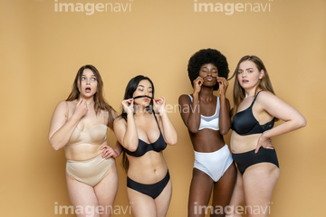 Multi-ethnic group of women wearing bras and jeans against wall