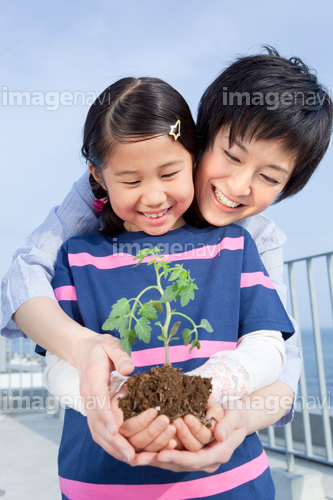 植物の苗を持って立つ母と娘