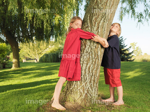 Young boy and girl hugging tree