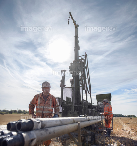 Workers operating drilling rig in field
