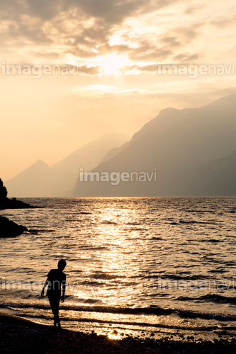 Italy, Veneto, Malcesine, Boy standing at Lake Garda in evening light