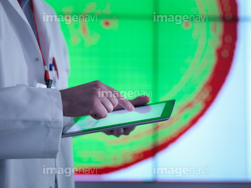 Scientist using digital tablet in front of graphical display of silicon wafer on screens, close up