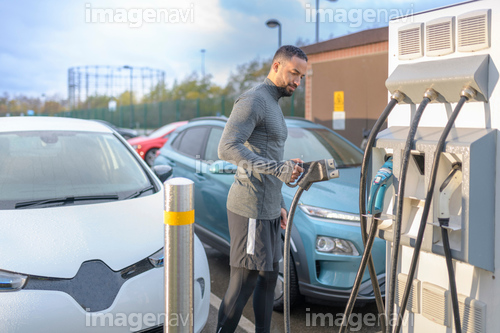 Sportsman at electric car charging point, Manchester, UK