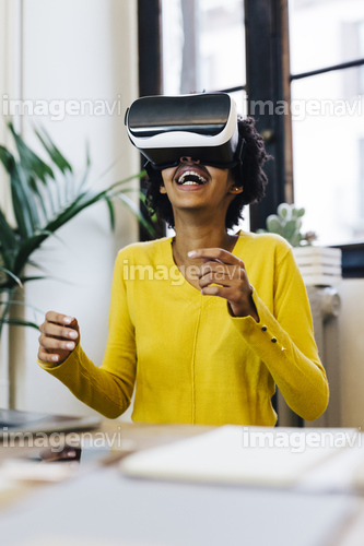 Laughing young woman playing game, wearing virtual reality goggles