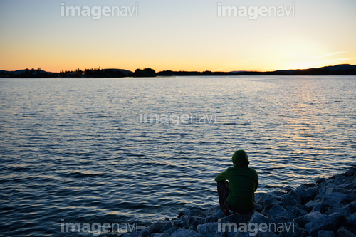 Sweden, Storuman, Man by the lakeside at sunset