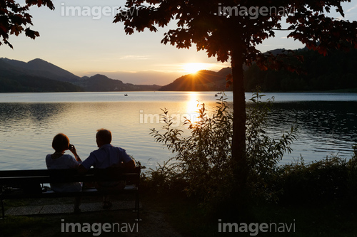 Austria, Salzburg State, Fuschlsee Lake, Fuschl am See, Couple on bench at sunset